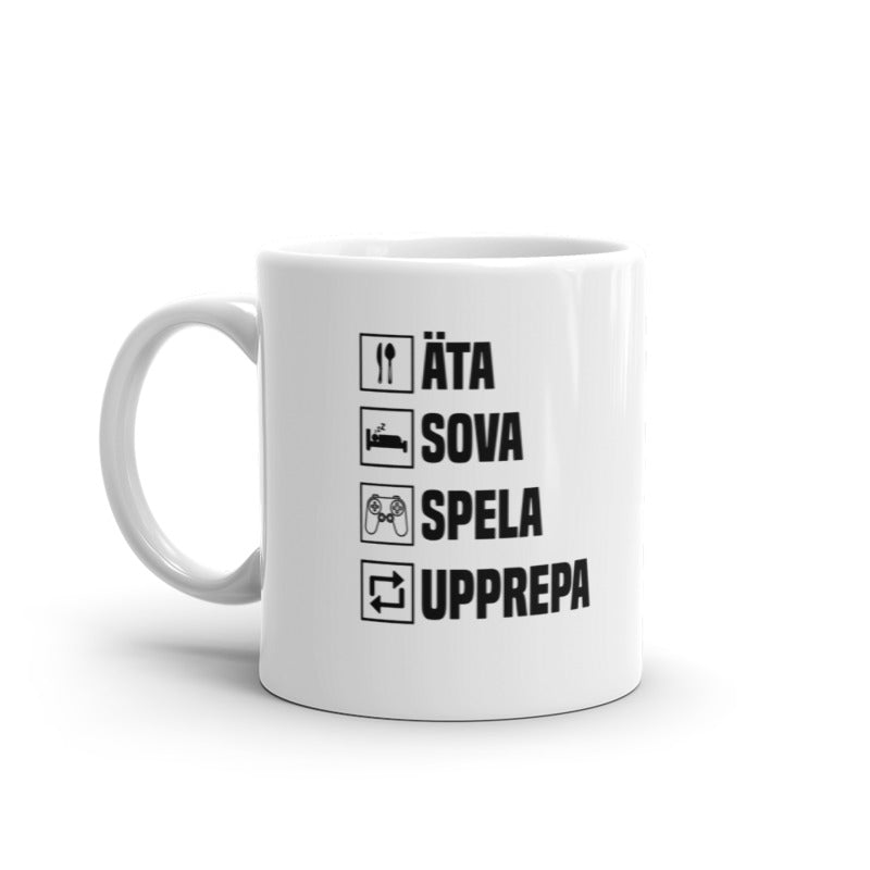 Porslinsmugg med texten "Äta, sova, spela, upprepa"